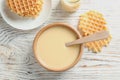 Bowl of condensed milk and waffles served on wooden table, top view. Royalty Free Stock Photo