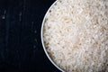 Bowl containing uncooked white rice on a black background. Top view. Close-up. Background and texture. Royalty Free Stock Photo