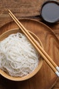 Bowl with cooked rice noodles, soy sauce and chopsticks on wooden table, flat lay Royalty Free Stock Photo