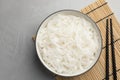 Bowl with cooked rice noodles, straw mat and chopsticks on light grey table, top view Royalty Free Stock Photo