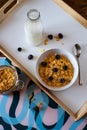 Bowl of corn flakes with blackberries next to the milk and corn flake jars