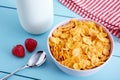 Bowl of corn flakes cereal, strawberries, a bottle of milk, napkin and spoon on blue wooden country style table. Royalty Free Stock Photo