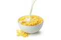 Bowl of corn flakes and flowing milk isolated on white background