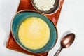 Bowl of corn porridge with butter and cheese on white paper background close up. Royalty Free Stock Photo