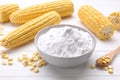 Bowl of corn starch, ripe cobs and kernels on white wooden table Royalty Free Stock Photo