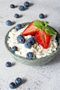 A bowl with cottage cheese, yogurt, fresh berries blueberries, strawberries and fresh mint on a gray background. Royalty Free Stock Photo