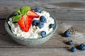 A bowl with cottage cheese, yogurt, fresh berries blueberries, strawberries and fresh mint on a wooden background. Royalty Free Stock Photo