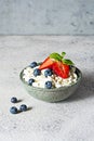 A bowl with cottage cheese, yogurt, fresh berries blueberries, strawberries and fresh mint on a gray background. Royalty Free Stock Photo