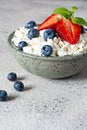 A bowl with cottage cheese, yogurt, fresh berries blueberries, strawberries and fresh mint on a gray background. Royalty Free Stock Photo