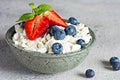 A bowl with cottage cheese, yogurt, fresh berries blueberries, strawberries and fresh mint on a gray background. Royalty Free Stock Photo