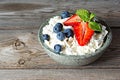 A bowl with cottage cheese, yogurt, fresh berries blueberries, strawberries and fresh mint on a wooden background. Royalty Free Stock Photo