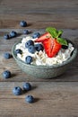 A bowl with cottage cheese, yogurt, fresh berries blueberries, strawberries and fresh mint on a wooden background. Royalty Free Stock Photo