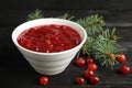 Bowl of cranberry sauce with fir tree branches on wooden background Royalty Free Stock Photo