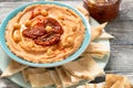 A bowl of creamy homemade hummus with with sun-dried tomatoes, olive oil and pita chips. traditional vegan healthy meal