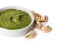 Bowl of creamy pistachio butter and nuts on white background, closeup