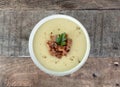 Bowl of creamy potato or cauliflower soup with bacon on a wooden background. Top view. French vichyssoise soup.