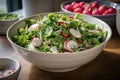 a bowl of crisp salad, topped with radishes, sunflower seeds and a squeeze of lemon