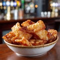 Bowl of crispy pork cracklings in a cozy bar setting. Royalty Free Stock Photo