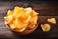 A bowl of crispy potato chips on a wooden table, a staple food Royalty Free Stock Photo