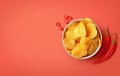 Bowl of crispy wavy potato chips or crisps with chili pepper flavor on red background Royalty Free Stock Photo