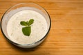 Bowl of cucumber yoghurt salad dressing on wooden background