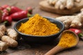 Bowl of curcuma ground to powder and whole turmeric roots. Red chilli pepper pods and ginger roots on background. Royalty Free Stock Photo