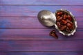 Bowl with dates on blue-violet wooden background. Flat lay