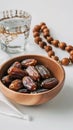 a bowl of dates, a prayer beads, a glass and a copy of the Holy Quran over white background Royalty Free Stock Photo