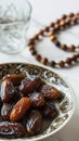 a bowl of dates, a prayer beads, a glass and a copy of the Holy Quran over white background Royalty Free Stock Photo
