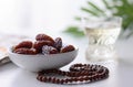 a bowl of dates, a prayer beads, a glass and a copy of the Holy Quran over white background Royalty Free Stock Photo