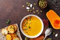 Bowl with delicious autumn pumpkin cream soup served with seeds and crouton on stone table from above