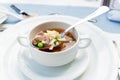 A bowl of delicious beef and barley soup with carrots, tomato, potato, celery, and peas.