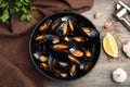 Bowl of delicious cooked mussels with parsley, garlic and lemon on wooden table, flat lay Royalty Free Stock Photo