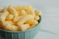 Bowl of delicious crispy corn sticks on white marble table, closeup