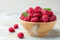 Bowl of delicious fresh ripe raspberries with leaves on wooden table, space for Royalty Free Stock Photo