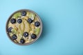 Bowl of delicious fruit smoothie with fresh blueberries, kiwi slices and coconut flakes on light blue background, top view. Space Royalty Free Stock Photo