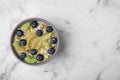 Bowl of delicious fruit smoothie with fresh blueberries, kiwi slices and coconut flakes on white marble table, top view. Space for Royalty Free Stock Photo