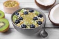 Bowl of delicious fruit smoothie served with fresh blueberries, kiwi slices and coconut flakes on white wooden table, closeup Royalty Free Stock Photo