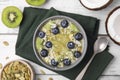 Bowl of delicious fruit smoothie served with fresh blueberries, kiwi slices and coconut flakes on white wooden table, flat lay Royalty Free Stock Photo