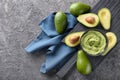 Bowl with delicious guacamole and ripe avocados on grey textured background Royalty Free Stock Photo