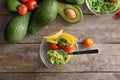 Bowl with delicious guacamole, vegetables and nachos on wooden table