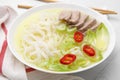 Bowl of delicious rice noodle soup with celery and meat on white tiled table, closeup Royalty Free Stock Photo
