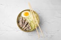 Bowl of delicious rice noodle soup with meat and egg on white textured table, top view Royalty Free Stock Photo