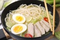 Bowl of delicious rice noodle soup with meat and egg on wooden board, closeup Royalty Free Stock Photo