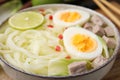 Bowl of delicious rice noodle soup with meat and egg on wooden board, closeup Royalty Free Stock Photo