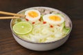 Bowl of delicious rice noodle soup with meat and egg on wooden table, closeup Royalty Free Stock Photo