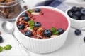 Bowl of delicious smoothie,served with fresh blueberries and granola on white tiled table, closeup Royalty Free Stock Photo