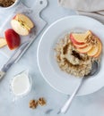 Bowl of steel cut oats and brown sugar topped with apple slices with milk on the side ready for pouring.