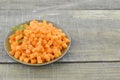 Bowl with diced carrots and parsley on wooden table, closeup