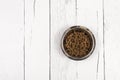 Bowl with dog kibble on white wooden planks